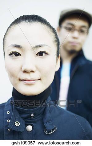 Stock Photo - Portrait of a young woman with a young man standing behind her. Fotosearch
