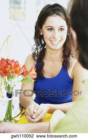 Stock Image - Close-up of a young woman and a man smiling in a restaurant. Fotosearch