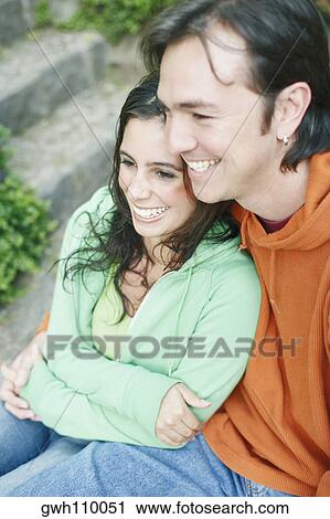 Stock Image - High angle view of a young woman and a mid adult man embracing each other and smiling. Fotosearch