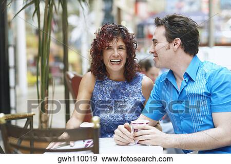 Stock Photo - Mature woman and a mid adult man sitting in a cafe. Fotosearch