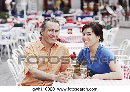 Portrait of a mature man and a young woman sitting together at a sidewalk cafe View Large Photo Image Stock Image - Portrait of a mature man and a young woman sitting together at a sidewalk cafe . Fotosearch