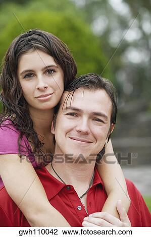 Stock Image - Portrait of a young woman embracing a mid adult man from behind. Fotosearch