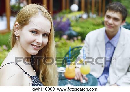 Portrait of a young woman smiling with a young man sitting with her View Large Photo Image Stock Photo - Portrait of a young woman smiling with a young man sitting with her . Fotosearch