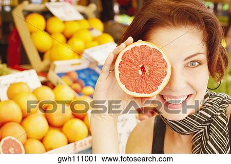 Stock Image - Close-up of a young woman holding half a grape fruit . Fotosearch