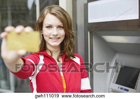 Portrait of a teenage girl holding an ATM card View Large Photo Image Stock Photo - Portrait of a teenage girl holding an ATM card . Fotosearch