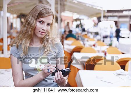 Stock Image - Portrait of a young woman holding a personal data assistant . Fotosearch