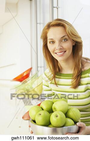 Portrait of a young woman holding a bowl of green apples View Large Photo Image Stock Image - Portrait of a young woman holding a bowl of green apples. Fotosearch