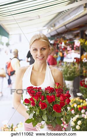 Stock Image - Portrait of a young woman holding a bouquet of flowers in a flower shop . Fotosearch