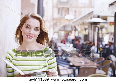 Stock Photo - Portrait of a young woman holding a menu card . Fotosearch