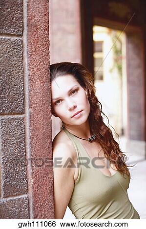 Stock Photograph - Portrait of a young woman leaning against a wall . Fotosearch