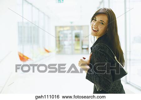 Stock Photograph - Portrait of a young woman looking back and smiling. Fotosearch
