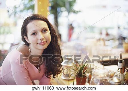 Portrait of a young woman sitting in a restaurant View Large Photo Image Stock Image - Portrait of a young woman sitting in a restaurant . Fotosearch