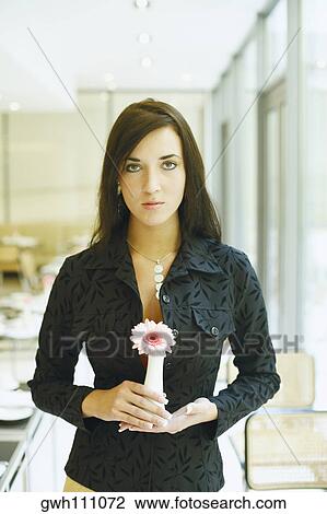 Portrait of a young woman standing in a restaurant and holding a flower vase View Large Photo Image Stock Image - Portrait of a young woman standing in a restaurant and holding a flower vase . Fotosearch