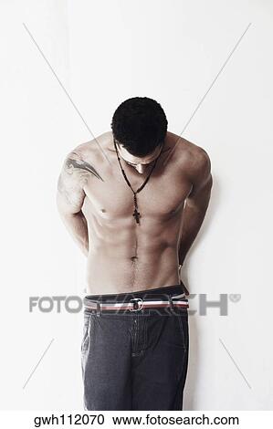 Stock Image - Close-up of a bare chested mid adult man looking down. Fotosearch