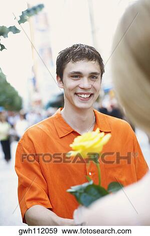 Close-up of a young man holding a flower View Large Photo Image Stock Photo - Close-up of a young man holding a flower. Fotosearch