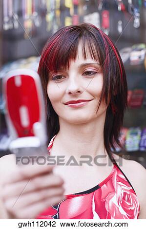 Low angle view of a young woman holding a mobile phone View Large Photo Image Stock Image - Low angle view of a young woman holding a mobile phone. Fotosearch