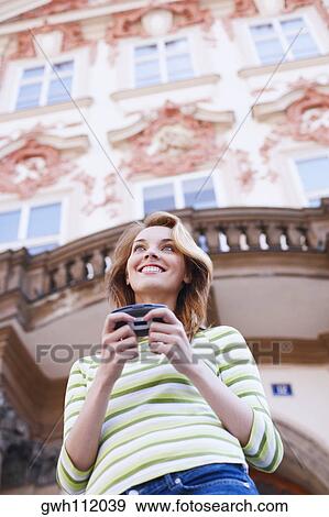 Low angle view of a young woman holding a mobile phone View Large Photo Image Stock Photo - Low angle view of a young woman holding a mobile phone . Fotosearch