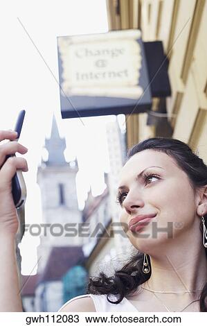 Low angle view of a young woman looking at a mobile phone View Large Photo Image Stock Image - Low angle view of a young woman looking at a mobile phone . Fotosearch