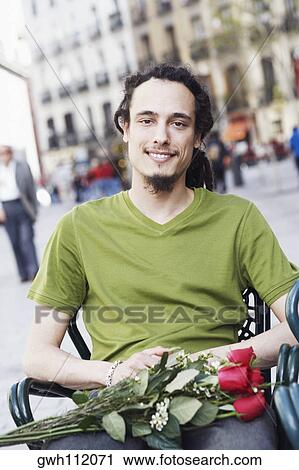 Portrait of a young man sitting on a chair with a bunch of roses on his lap View Large Photo Image Stock Image - Portrait of a young man sitting on a chair with a bunch of roses on his lap . Fotosearch