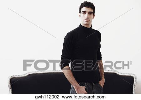 Portrait of a young man standing with his hands in his pockets View Large Photo Image Stock Image - Portrait of a young man standing with his hands in his pockets. Fotosearch