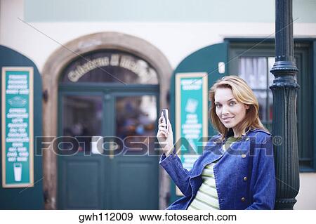 Stock Photo - Portrait of a young woman holding a mobile phone . Fotosearch