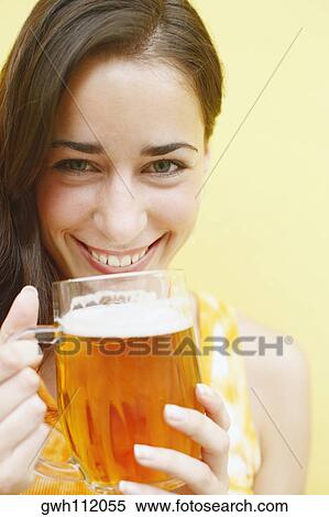 Portrait of a young woman holding a glass of beer View Large Photo Image Stock Photography - Portrait of a young woman holding a glass of beer . Fotosearch