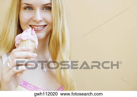 Portrait of a young woman holding an ice-cream cone View Large Photo Image Stock Image - Portrait of a young woman holding an ice-cream cone. Fotosearch