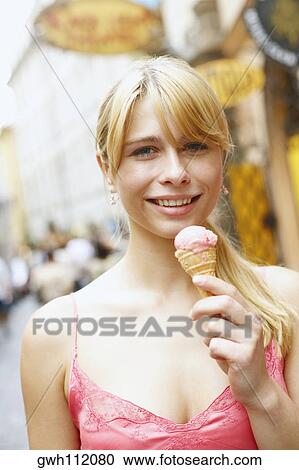 Portrait of a young woman holding an ice-cream cone View Large Photo Image Stock Image - Portrait of a young woman holding an ice-cream cone. Fotosearch