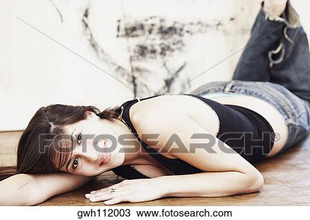 Stock Image - Portrait of a young woman lying on the floor. Fotosearch