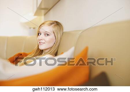 Portrait of a young woman sitting on a couch View Large Photo Image Stock Image - Portrait of a young woman sitting on a couch. Fotosearch
