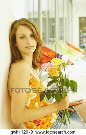Side profile of a teenage girl sitting and holding a bouquet of flowers View Large Photo Image Stock Photo - Side profile of a teenage girl sitting and holding a bouquet of flowers. Fotosearch