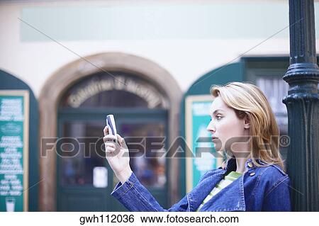 Side profile of a young woman holding a mobile phone View Large Photo Image Stock Photograph - Side profile of a young woman holding a mobile phone . Fotosearch