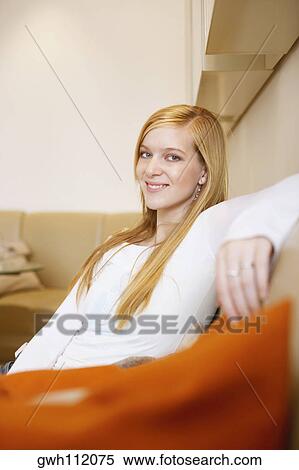 Side profile of a young woman sitting on a couch View Large Photo Image Stock Photography - Side profile of a young woman sitting on a couch. Fotosearch