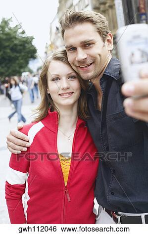 Stock Photograph - Teenage couple holding a mobile phone for a photograph . Fotosearch