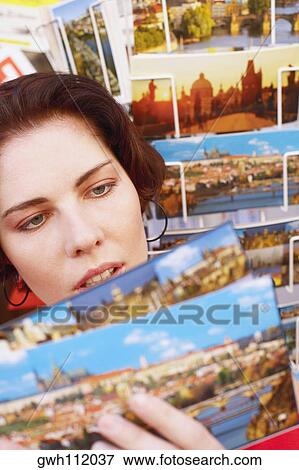 Stock Photo - Young woman looking at postcards . Fotosearch