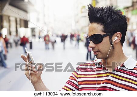 Picture - Close-up of a young man listening to an MP3 Player . Fotosearch