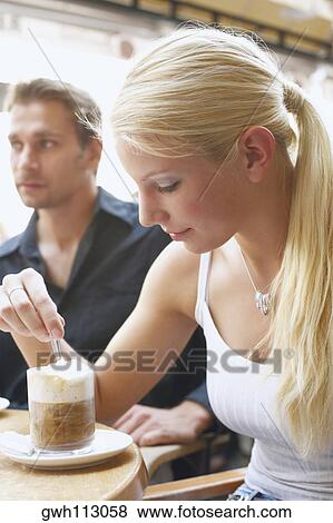 Stock Photo - Close-up of a young woman and a young man seated at a table. Fotosearch