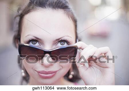 Close-up of a young woman holding sunglasses View Large Photo Image Picture - Close-up of a young woman holding sunglasses . Fotosearch