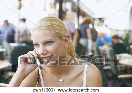 Close-up of a young woman talking on a mobile phone in a restaurant View Large Photo Image Stock Photo - Close-up of a young woman talking on a mobile phone in a restaurant . Fotosearch