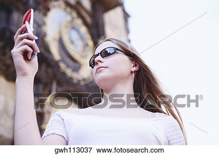Low angle view of a young woman holding a mobile phone View Large Photo Image Stock Photo - Low angle view of a young woman holding a mobile phone . Fotosearch