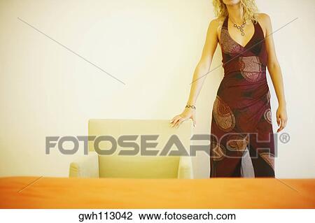 Mid section view of a young woman standing near an armchair View Large Photo Image Stock Image - Mid section view of a young woman standing near an armchair. Fotosearch