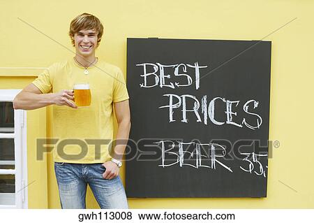 Portrait of a young man holding a glass of beer View Large Photo Image Stock Photo - Portrait of a young man holding a glass of beer . Fotosearch