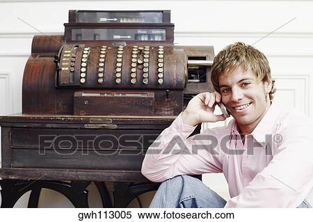 Stock Photography - Portrait of a young man talking on a mobile phone near a typewriter. Fotosearch
