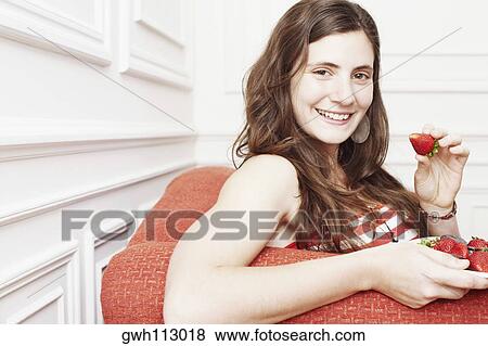 Portrait of a young woman holding a plate of strawberries and smiling View Large Photo Image Stock Photo - Portrait of a young woman holding a plate of strawberries and smiling. Fotosearch
