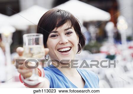 Portrait of a young woman holding up a glass of white wine View Large Photo Image Stock Image - Portrait of a young woman holding up a glass of white wine . Fotosearch