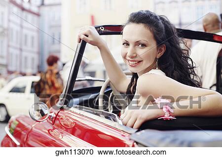 Portrait of a young woman sitting in a car and smiling View Large Photo Image Stock Image - Portrait of a young woman sitting in a car and smiling . Fotosearch