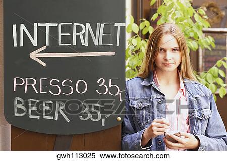 Portrait of a young woman standing against a signboard View Large Photo Image Stock Photography - Portrait of a young woman standing against a signboard . Fotosearch