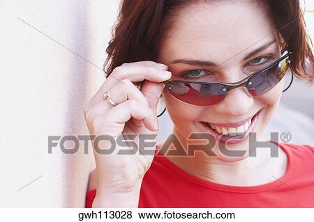 Portrait of a young woman wearing sunglasses and smiling View Large Photo Image Stock Photo - Portrait of a young woman wearing sunglasses and smiling. Fotosearch