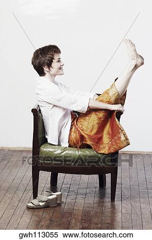 Side profile of a mid adult woman sitting in an armchair with her feet up View Large Photo Image Stock Photography - Side profile of a mid adult woman sitting in an armchair with her feet up. Fotosearch