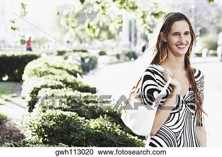 Young woman carrying a hand bag and smiling View Large Photo Image Stock Image - Young woman carrying a hand bag and smiling . Fotosearch
